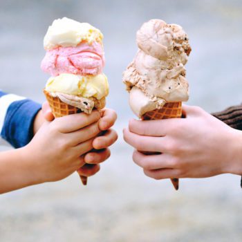 Two sets of hands holding waffle cones with scoops of Chapman's Ice Cream