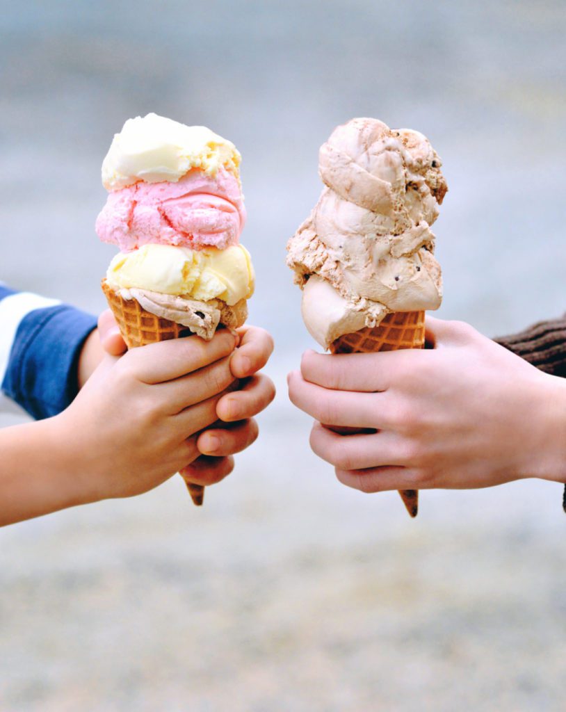 Two sets of hands holding waffle cones with scoops of Chapman's Ice Cream