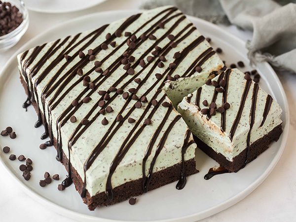 Mint Brownie Ice Cream Cake with a corner slice cut and angled slightly on top of a white plate