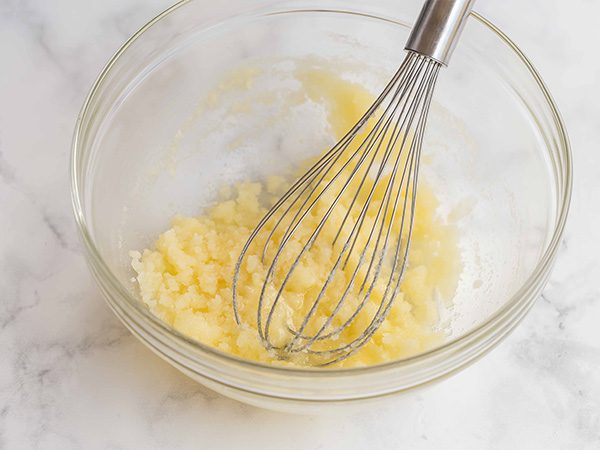 glass mixing bowl with a whisk mixing butter, eggs and sugar