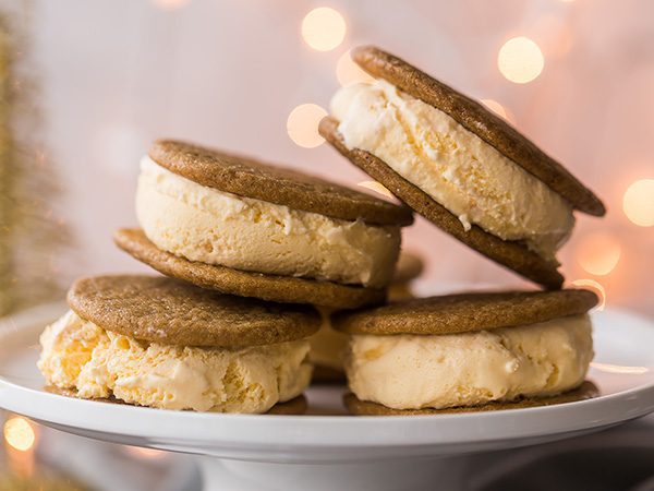 stack of four Shortbread & Spice ice cream sandwiches on a white platter with twinkly warm Christmas lights in the background