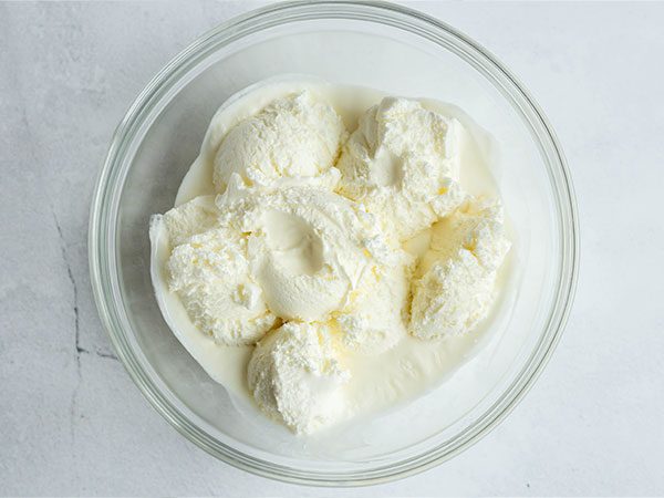 Scoops of vanilla ice cream slightly melted inside a clear mixing bowl