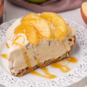 A slice of Caramel Apple Ice Cream Pie on a white decorative plate with a drizzle of caramel sauce on top.