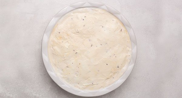 A white pie plate with a smooth layer of Caramel Praline ice cream spread evenly around.
