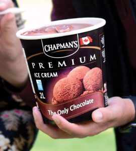 Close up of someone's hand holding an open tub of Chapman's Premium The Only Chocolate ice cream