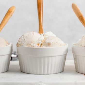 Three white bowls, filled with scoops of Butterscotch Ripple ice cream, aligned horizontally on a white marble board.