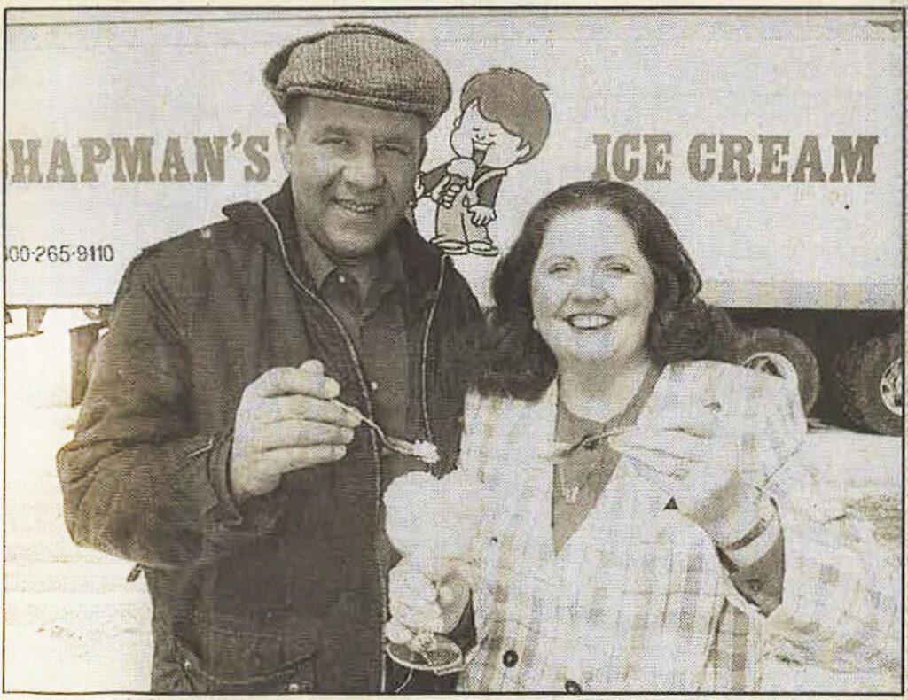 A black and white photo of David and Penny Chapman from the early 1970's. They're standing in front of a Chapman's truck, each with a spoonful of their new Sorbet.