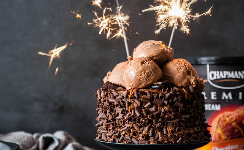 Chocolate Cake with Chocolate ice cream on top with lit sparklers with a dark grey background